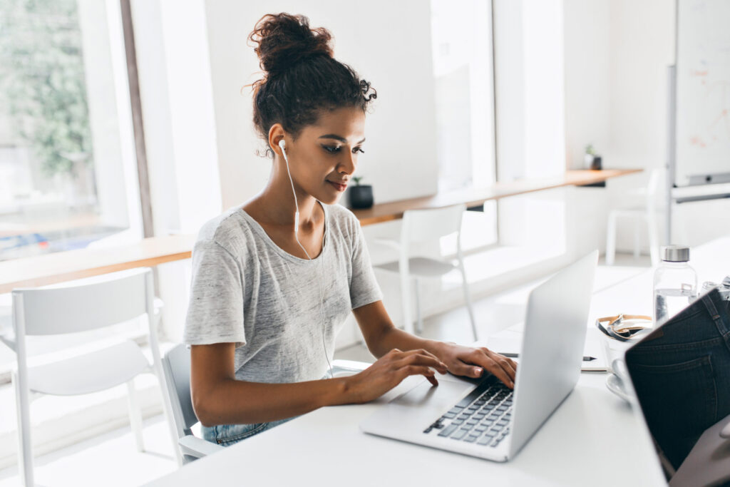 Black woman with trendy hairstyle sits in workplace analyzing data