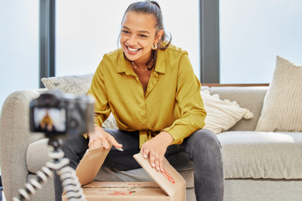An influencer speaks to a camera and smiles during an unboxing video
