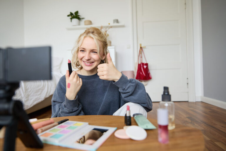 A female content creator promotes brand trust to her online audience, she is leading a makeup tutorial with her phone.
