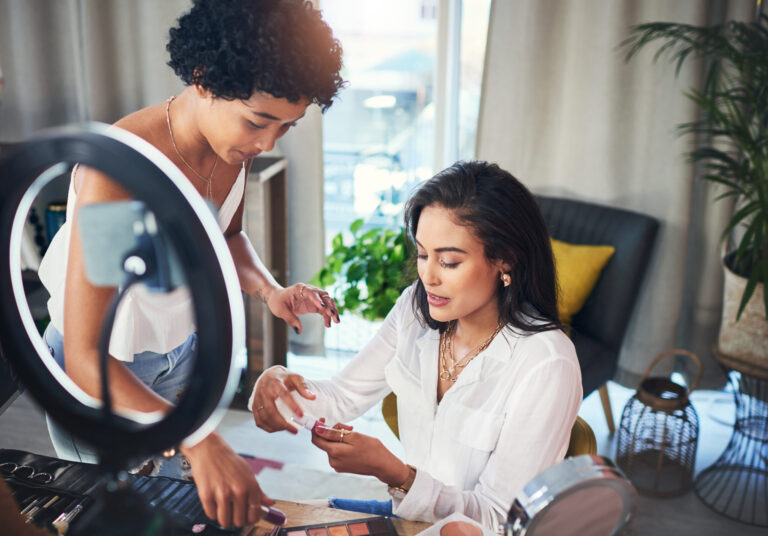 Two beauty influencers work together on a makeup tutorial