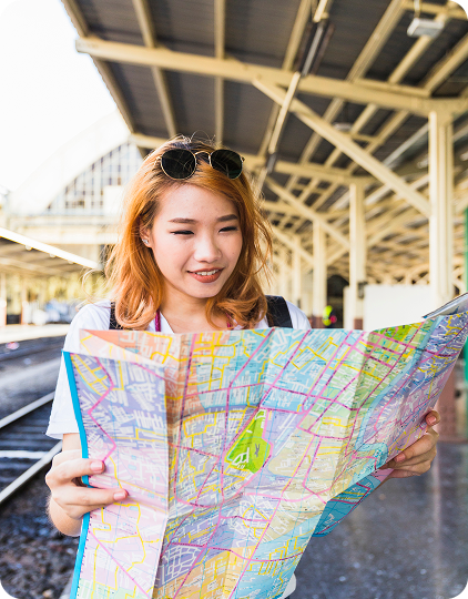 A travel influencer smiles while reading a map at a train station